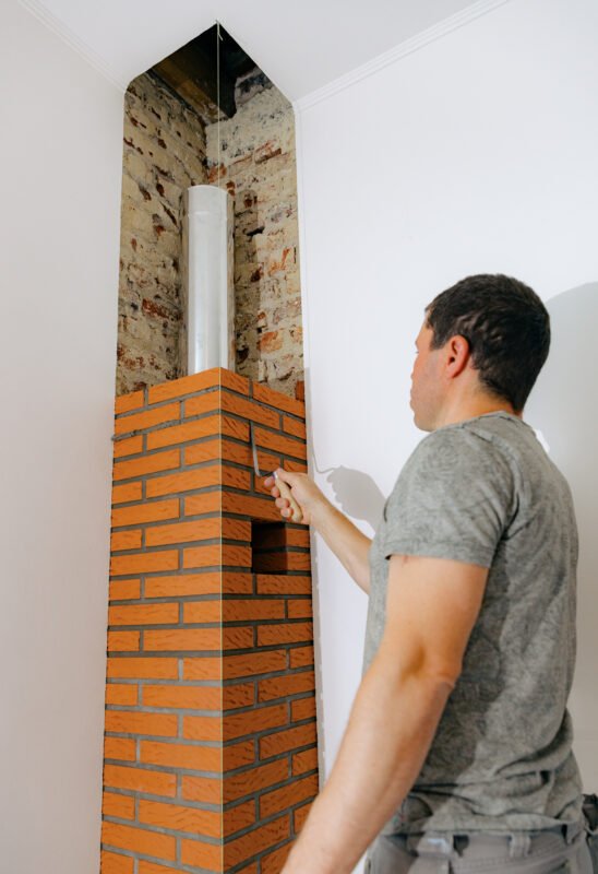 A young man makes brickwork on the chimney of a fireplace.