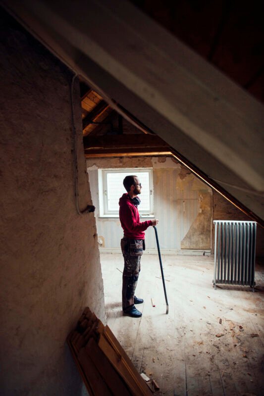 Full length side view of man with work tool renovating attic