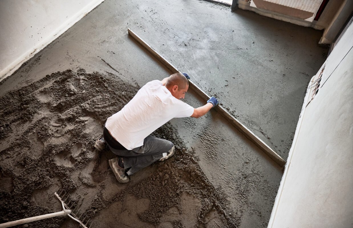 Man screeding floor in apartment during renovation.