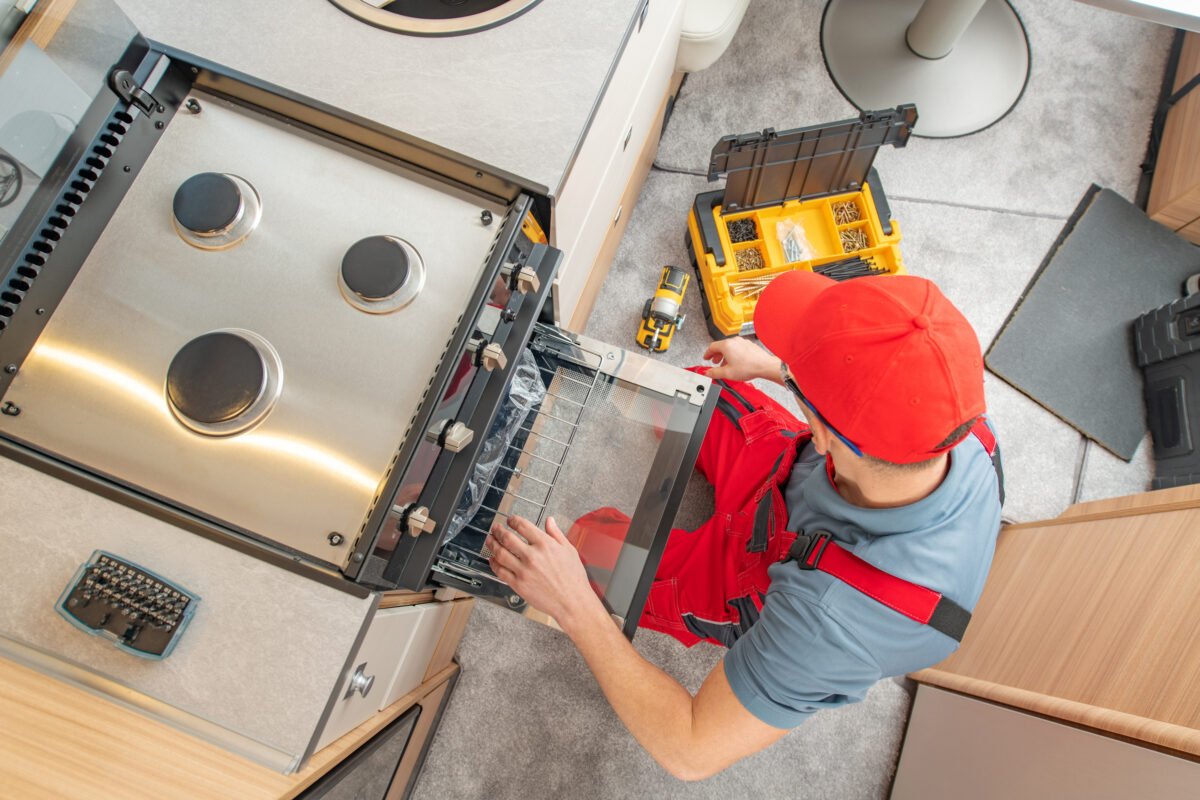 Technician Replacing Broken Travel Trailer Gas Stove